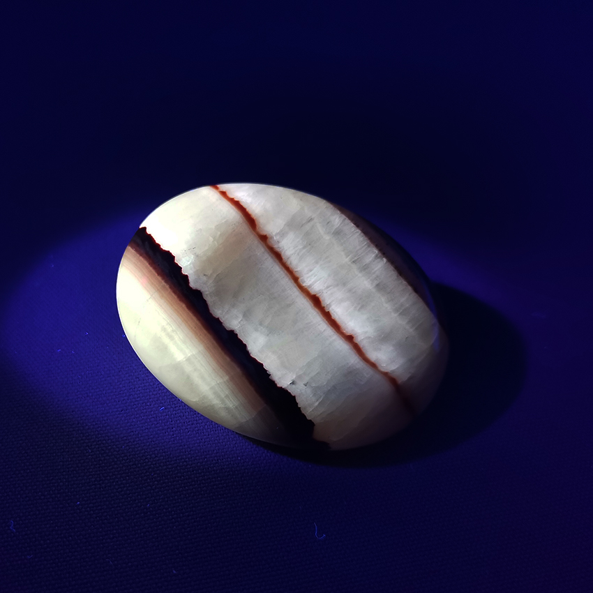 Peruvian Tiger Aragonite worry stone 02 under UV light